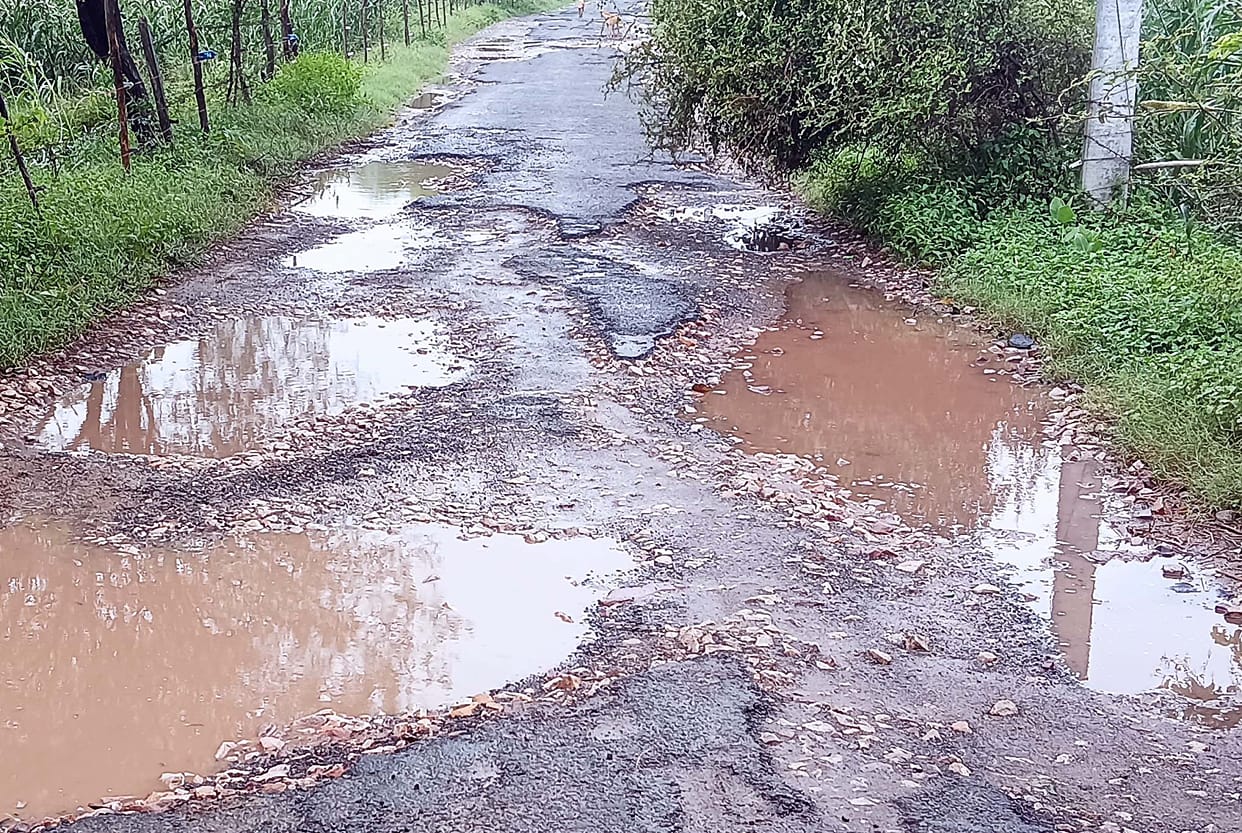 Road riddled with potholes; commuters face increased difficulties.