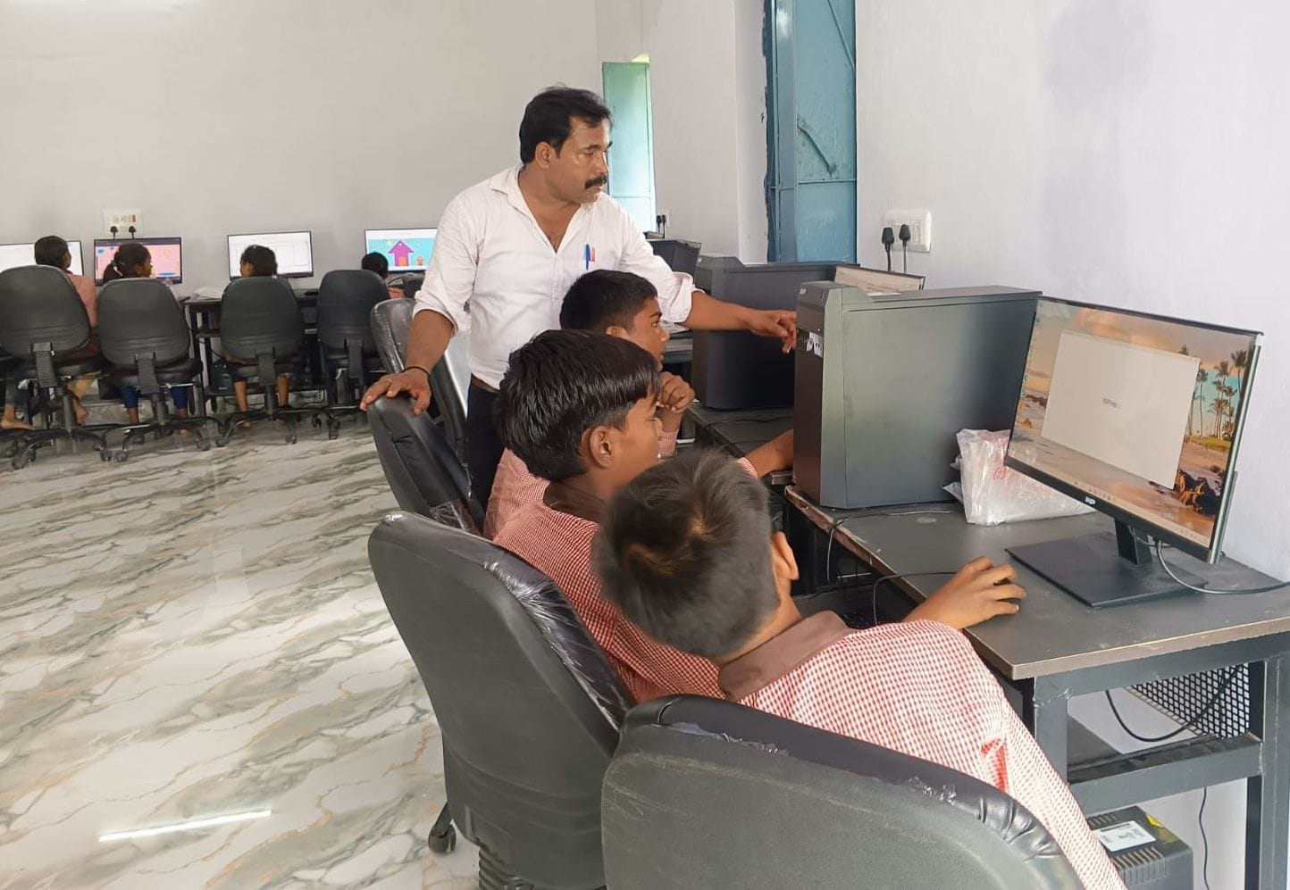 डिजिटल लाइब्रेरी में बच्चों का मार्गदर्शन करते इंचार्ज प्रधान शिक्षक। स्रोत: शिक्षक