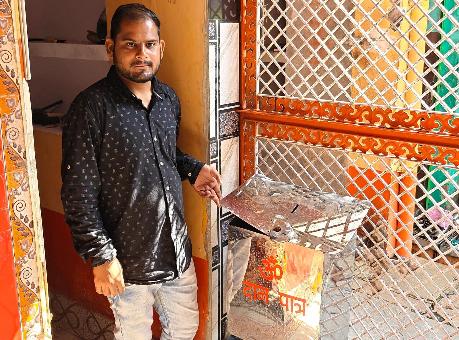 फोटो- 01 चोरी के बाद दान पेटिका को दिखाते पुजारी संदीप दुबे। संवाद