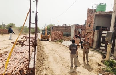 Bulldozer razes illegal colony; foundations uprooted.