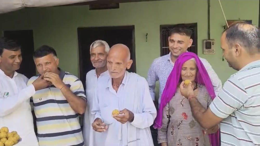 02जेएनडी04: कीर्ति शर्मा के पिता विजय, दादा रामजुआरी व दादी को मिठाई खिलाकर खुशी मनाते ग्रामीण