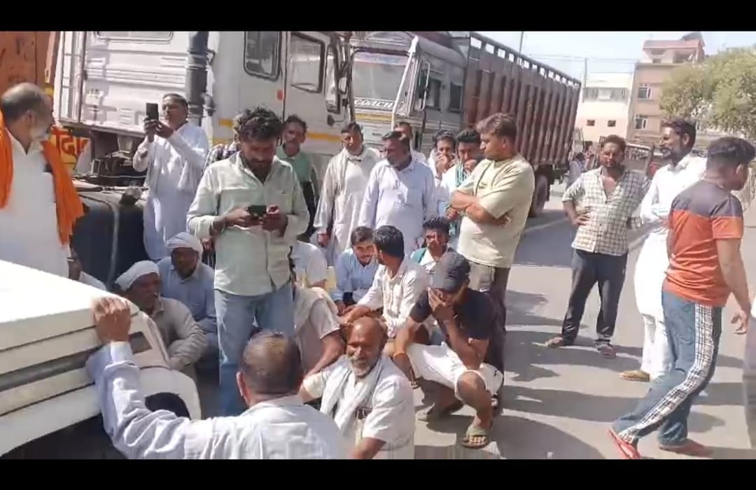 सिरसा में कृषि विभाग के अधिकारियों की गाड़ी के सामने बैठे किसान। संवाद