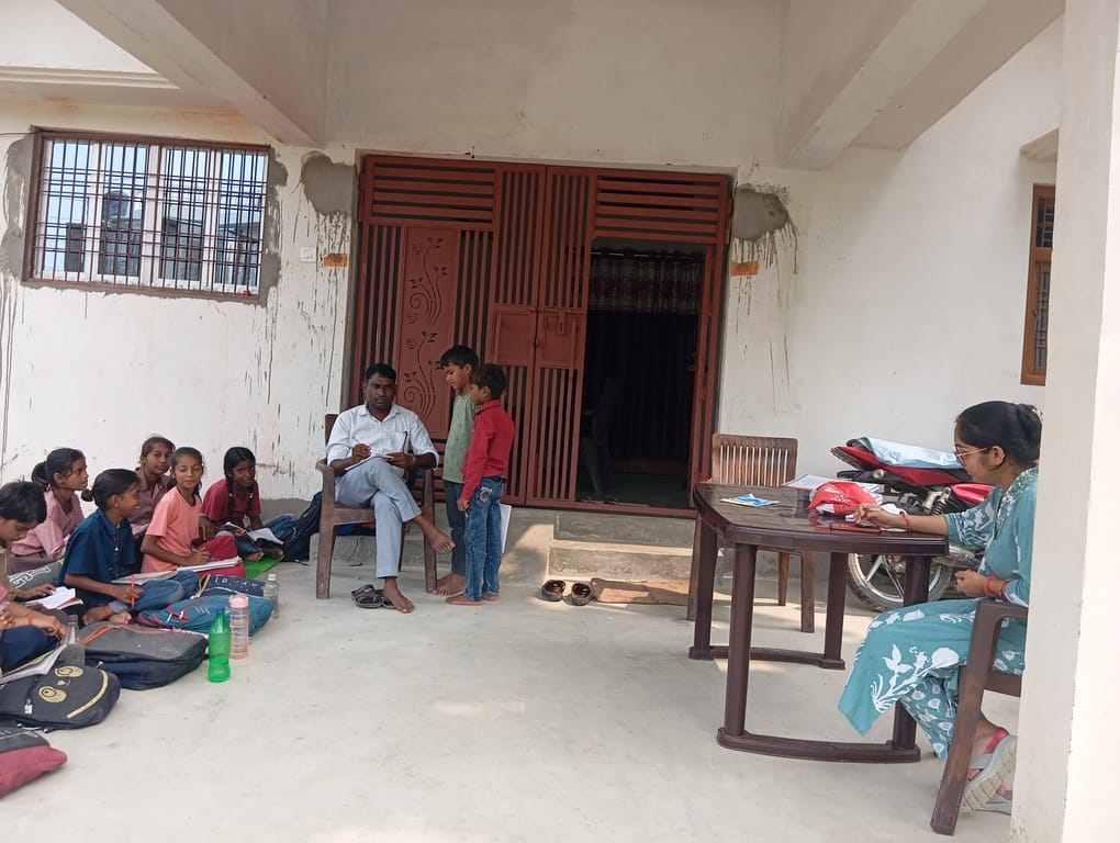 सिरसिया दीक्षित प्राथमिक विद्यालय के एक मकान के बरामदे में पढ़ते  बच्चे। 