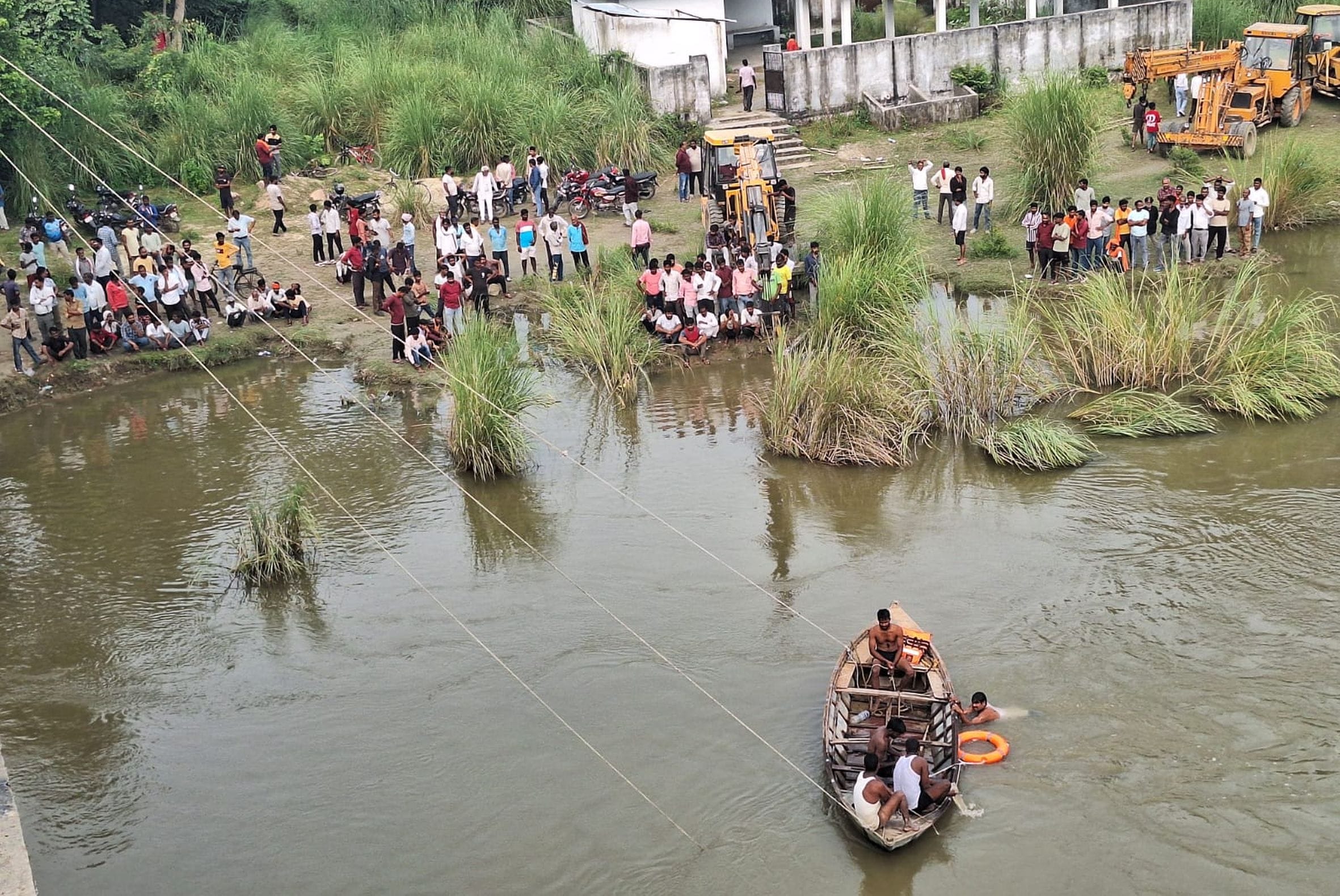 परशदेपुर क्षेत्र के सई नदी में गिरे चीनी के बोरे से लदे ट्रक को निकालने में जुटी गोताखोरों की ट