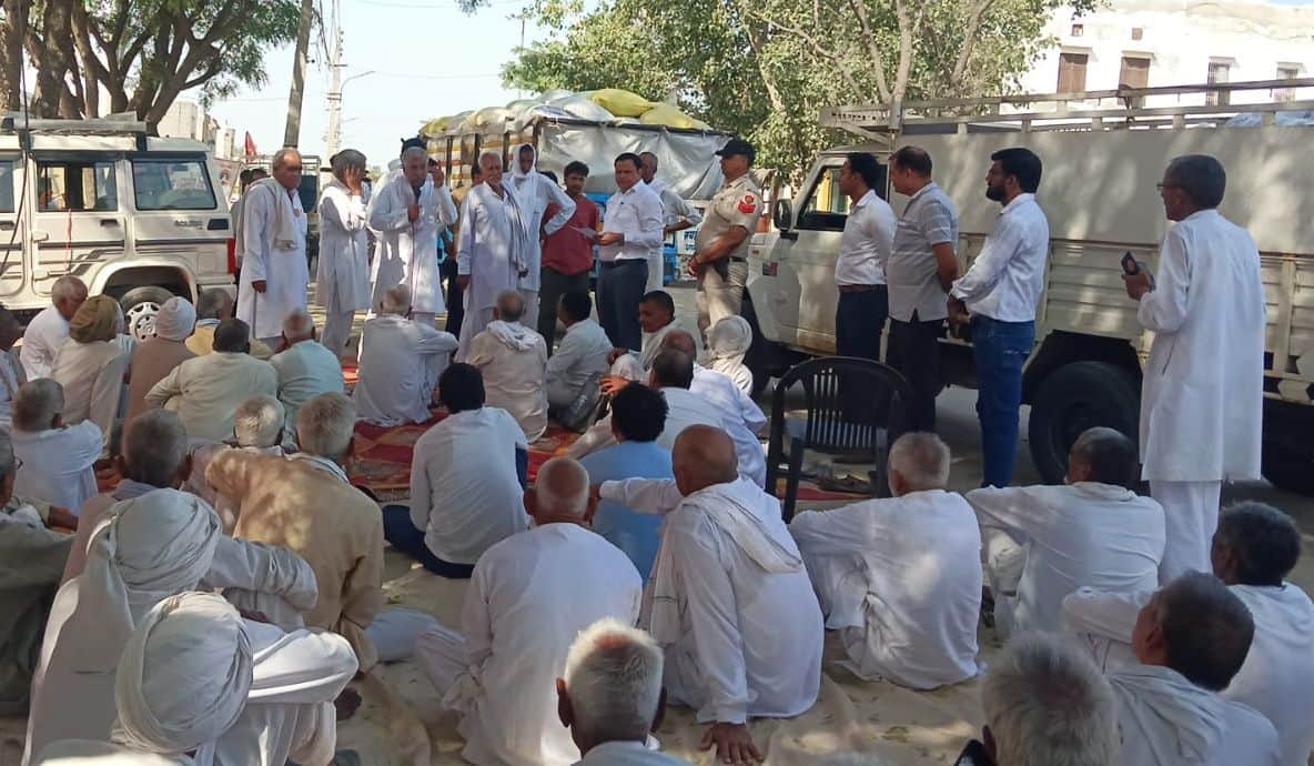 तोशाम अनाज मंडी धरने पर बैठ किसानों से बातचीत करते एसडीएम संदीप कुमार ।