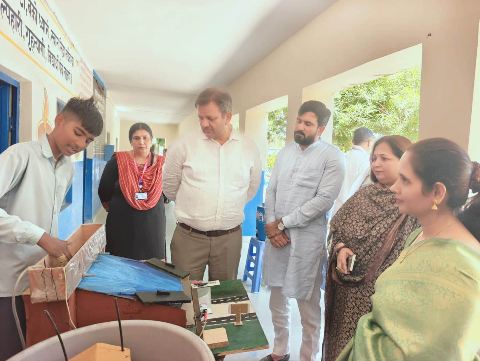 विज्ञान प्रदर्शनी में विद्यार्थियों द्वारा प्रस्तुत किए गए मॉडल देखते शिक्षक और अन्य विद्यार्थी