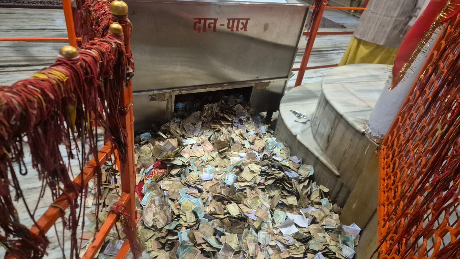खुला पड़ा दानपात्र का ढक्कन व नकदी। संवाद