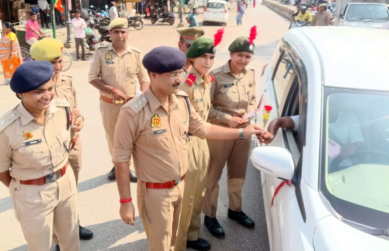 फोटो-18- सीटबेल्ट लगाकर जा रहे कार चालक को गुलाब का फूल देते सीओ यातायात अनुज मिश्रा व अन्य। सं