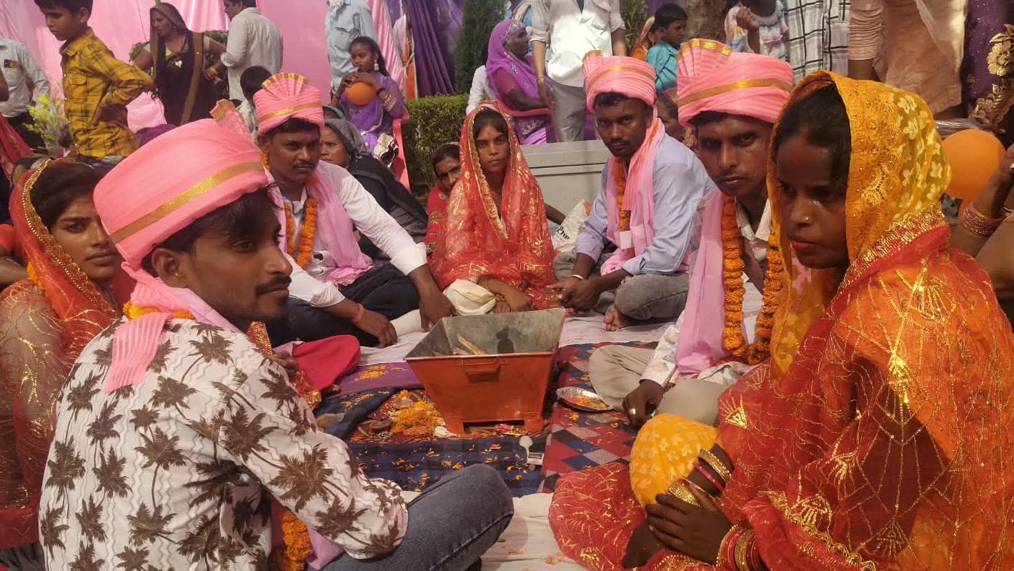 सामूहिक विवाह आयोजन में बैठे जोड़े। संवाद
