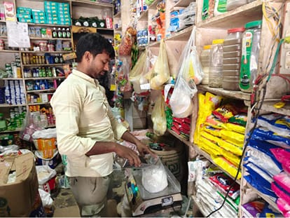 रगड़गंज स्थित एक किराना दुकान में ग्राहक के लिए चीनी तौलता दुकानदार। संवाद