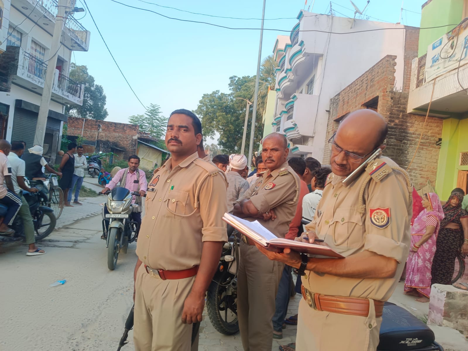 पल्हना रोड पर मृतक के घर पर लगी लोगों की भीड़, मौजूद पुलिस कर्मी। संवाद