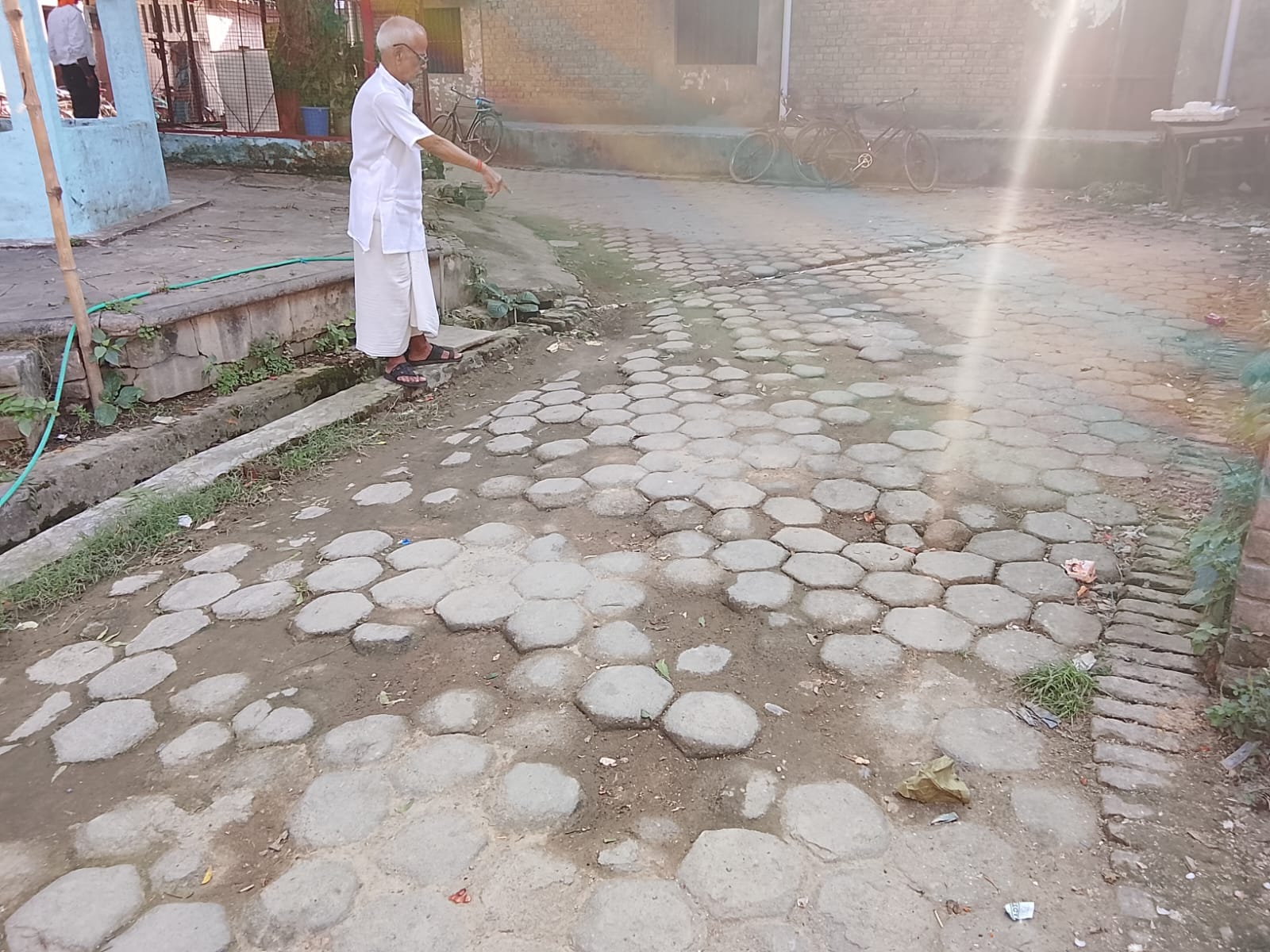 बदहाल सड़क को दिखाता व्यक्ति। संवाद