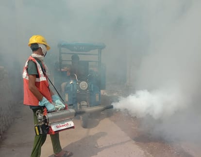 फोटो-23- हथगाम के तेउंजा गांव में डेंगू प्रभावित मरीज के घर के बाहर दवा का छिड़काव करते कर्मी। 