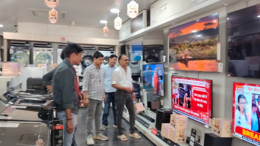 इलेक्ट्रॉनिक दुकान पर टीवी की खरीददारी करते ग्राहक - संवाद