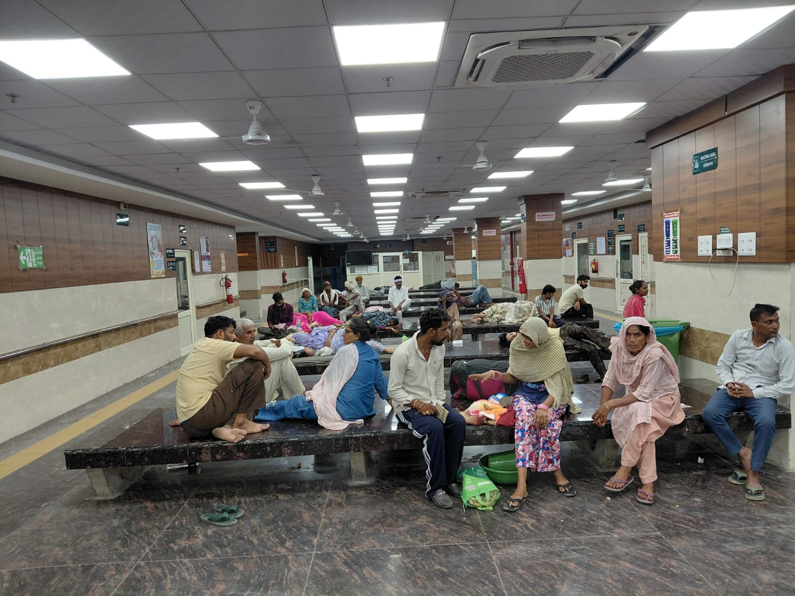 अस्पताल में उपचार के लिए आए हुए मरीज ओपीडी के बाहर बैठे हुए अपनी बारी का इंतजार करते हुए। संवाद