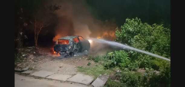 A car parked outside a house catches fire