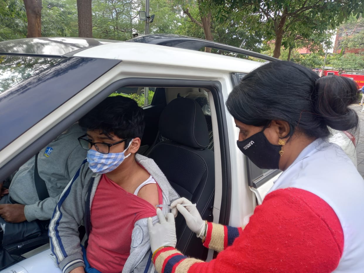 स्वास्थ्य विभाग की ओर से साइबर हब में चलाये गए ड्राइव थ्रू वैक्सीनेशन  अभियान के तहत  युवक को कोरोनारोधी वैक्सीन का टीका लगती हुई स्वास्थ्य कर्मी।