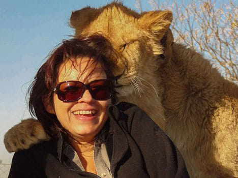 lioness puts forward her paws to lady's shoulder to get a selfie clicked