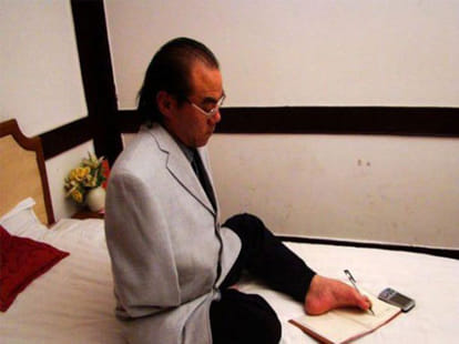 man threads eye of a needle with his toes