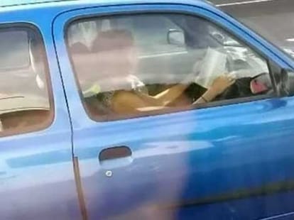 women drives car while reading a book