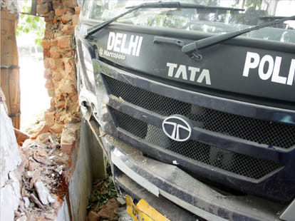 Police bus rams in roadside wall.